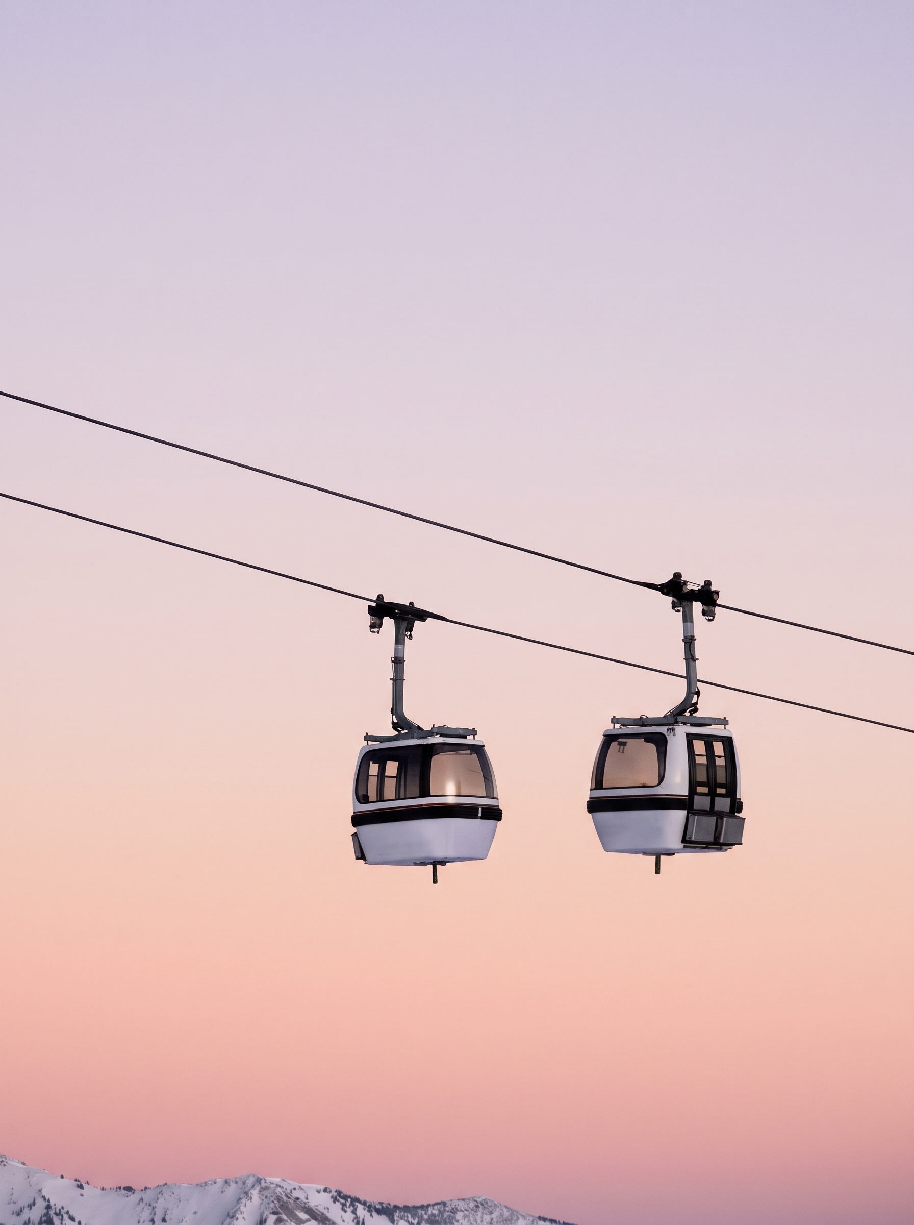 Cable cars above snow-capped mountains at dusk